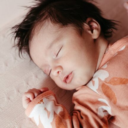 A serene image of a baby peacefully sleeping in a floral outfit, capturing the innocence of childhood.