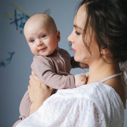 A mother joyfully holds her baby in a cozy indoor setting, highlighting family love and affection.