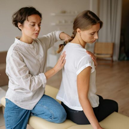 A female therapist provides a back massage therapy session to a client in a serene spa setting.