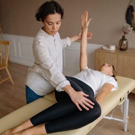 Physiotherapist aids woman with therapeutic exercises indoors.