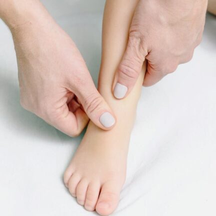 Hands gently massaging a child's foot, promoting relaxation and tenderness.